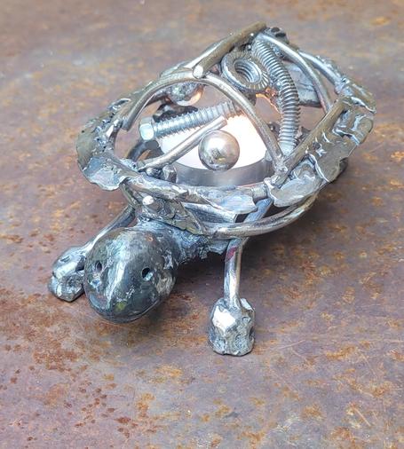 Éloge de la lenteur 
Une tortue chandelier en acier recyclé. Sa carapace s'enlève pour pouvoir changer le lampion. 
100% rebut