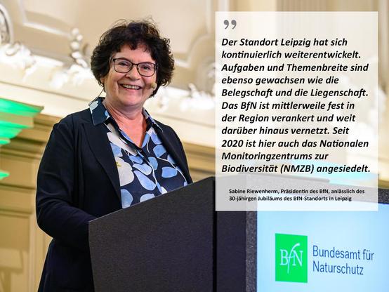 Sabine Riewenherm, Präsidentin des Bundesamtes für Naturschutz zum 30-jährigen Jubiläum des Bundesamtes am Standort Leipzig steht am Rednerpult. Das Zitat von Sabine Riewenherm: "Der Standort Leipzig hat sich kontinuierlich weiterentwickelt. Aufgaben und Themenbreite sind ebenso gewachsen wie die Belegschaft und die Liegenschaft. Darüber hinaus ist das BfN mittlerweile auch fest in der Region verankert und weit darüber hinaus vernetzt. Dazu hat auch die Ansiedlung des Nationalen Monitoringzentrum zur Biodiversität (NMZB) im Jahr 2020 beigetragen."