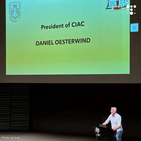 Mann steht an einem Rednerpult auf einer Bühne, im Hintergrund Projektion mit Text 'President of CIAC DANIEL OESTERWIND'.