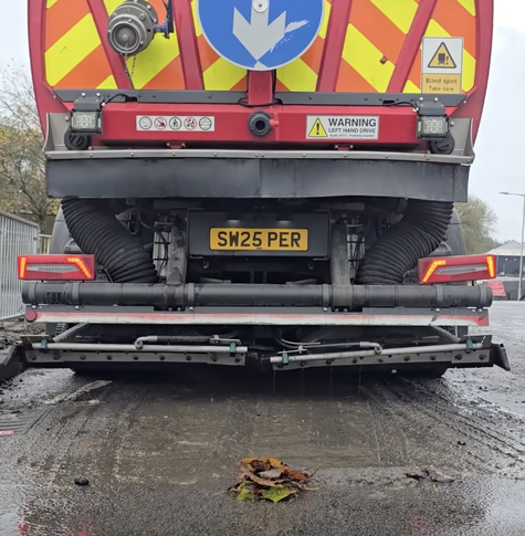 Rear view of road sweeper lorry with brushes working at Cwmbwrla roundabout.