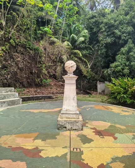 the landmark in são tomé e príncipe that marks the exact spot where the equator line divides the north from the south. it's an old landmark with the world map drawn on the floor and is surrounded by tropical forest