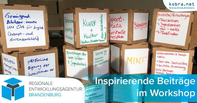 Während des Workshops wurden Pappwürfel mit den Ideen der Teilnehmenden beschrieben. Diese sind auf dem Foto in einer losen Wand von 3 mal 4 Würfeln aufgestapelt.