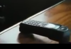 An Iridium 9505 resting on a table with the antenna flapped out