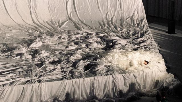 Eine riesige Bühne als überdimensionales ungemachtes Bett. Rechts unten im Bild und im Bett liegt Rosalia in Embryo-Position.