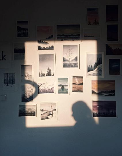 Shadow of the artist on the wall full of paintings.