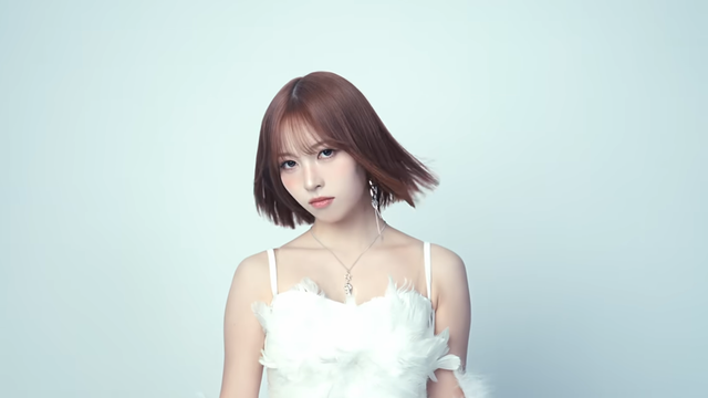 A portrait of a person with shoulder-length, reddish-brown hair against a pale blue background. The hair is styled with bangs and appears slightly wavy. The person is wearing a white, strapless top with a textured, feathered design. A delicate silver necklace with a small pendant is visible around the neck. The person is looking directly at the camera with a neutral expression.

Provided by @altbot, generated privately and locally using Gemma3:27b