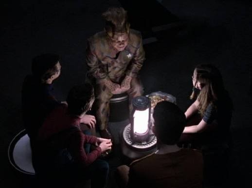 Neelix and Borg kids sitting in a darkened cargo bay campfire style
