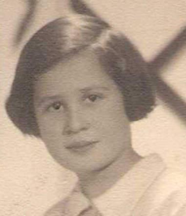 A portrait photo of a young girl looking into a camera. She has mid-length dark hair and wearing a blouse with a collar.