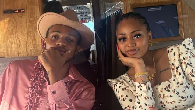 Sammy and Regina Daniels sitting side by side in a private jet, both resting their chins on their hands and looking at the camera.