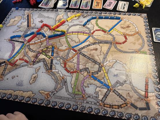 A game of Ticket to Ride Europe in the early stages of play. The board is a map of Europe with various cities and train routes marked on it. Claimed routes are marked with coloured plastic train pieces.