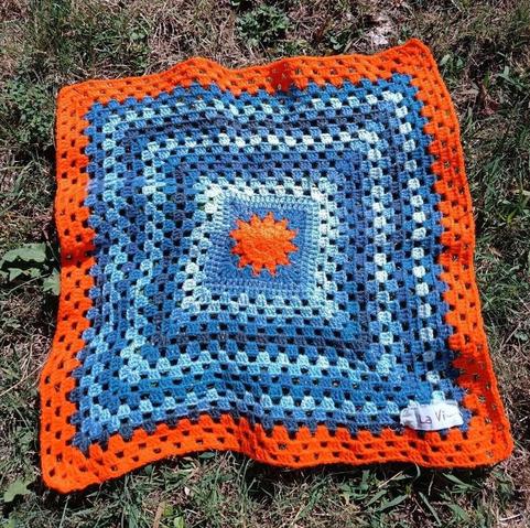 Quadrato Splendore: sole centrale e riquadri nei toni del blu, bordo arancione.