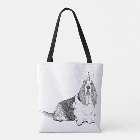 product image of a canvas tote bag with long black handles. The image on the front is a pen and ink stippled drawing of a sitting, noble looking basset hound with a glowing unicorn horn (his name is Fred.)