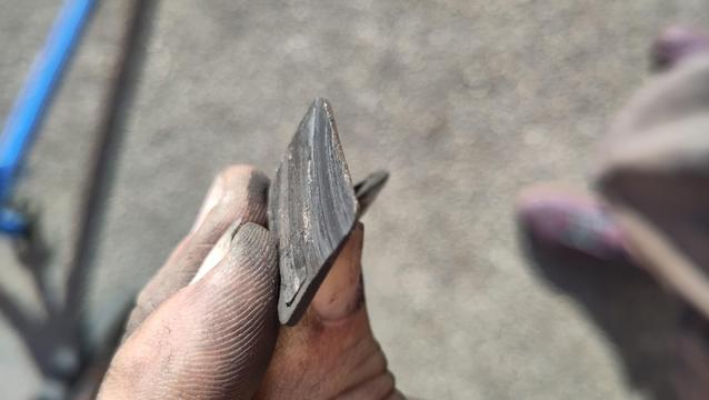 Plaquette de frein de vélo tenue à la main. La garniture est complètement usée et même le support est bouffé