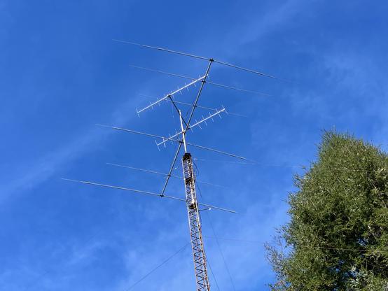 A triangular tower with a 6 element beam and perhaps an array for satellite work. The sky is deep blue with some clouds.