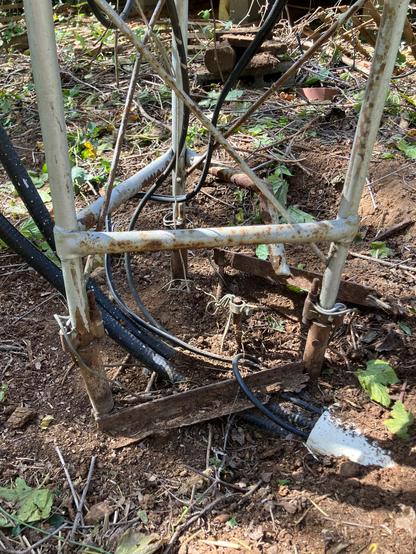 The rusted and broken base of the tower, with cables coming out of the ground and up through the tower.
