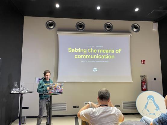 Harry showing the slide “Seizing the means of communication: a plan for community-owned social media”