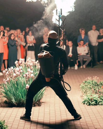 a man with a flamethrower stands in front of a crowd of people