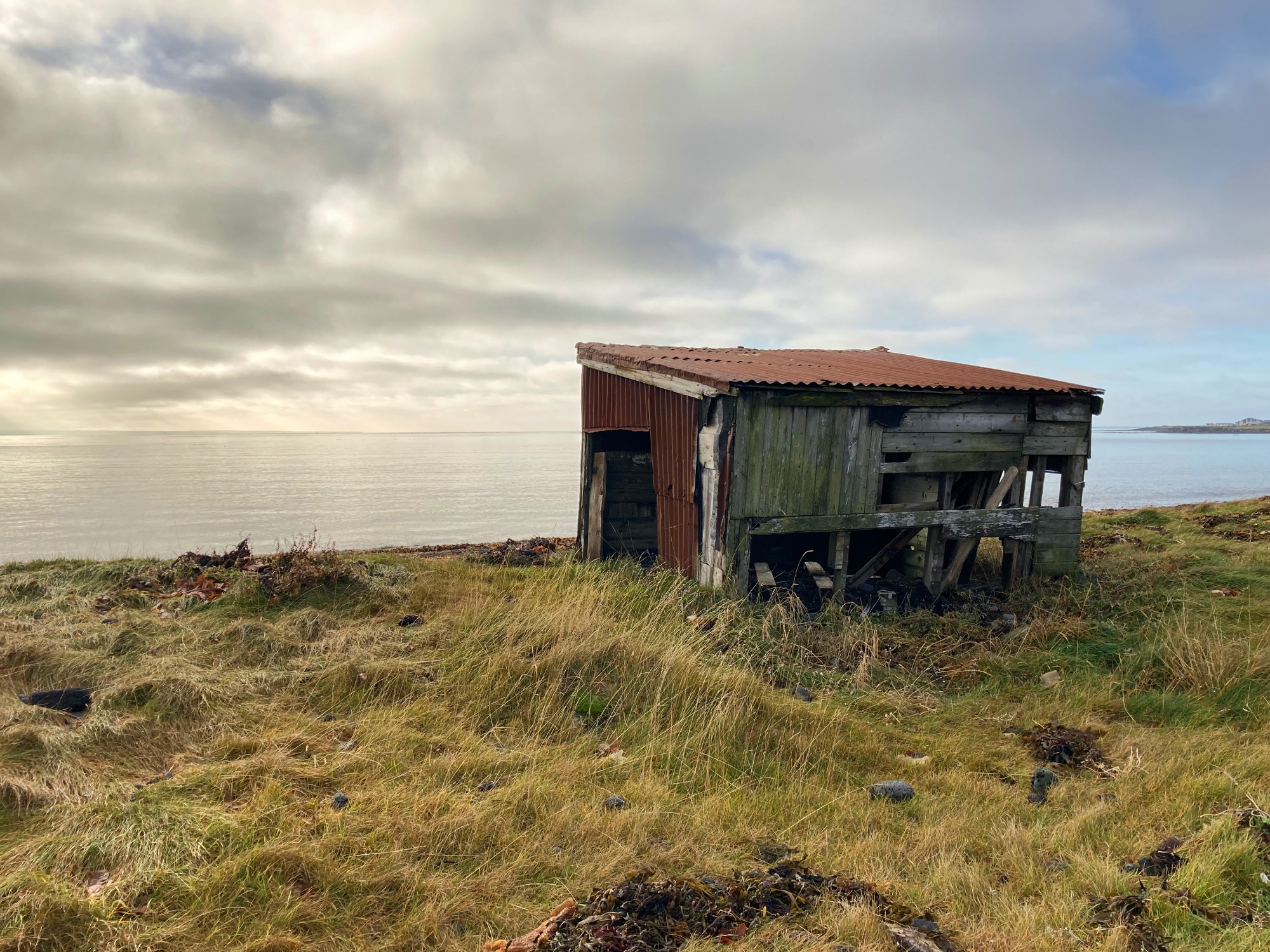 A tiny rusty shed next to the sea.
