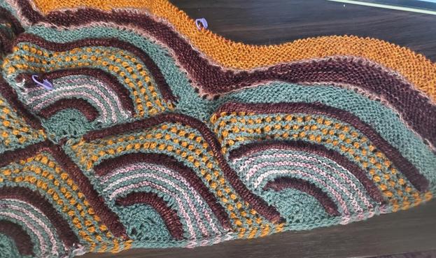 Four colored shawl on needles in various patterns and curves