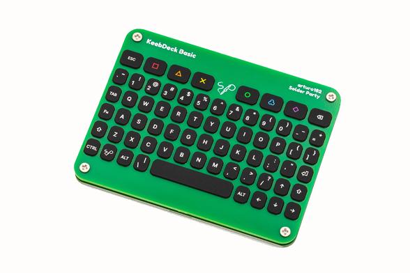 A photo of a device composed of two PCBs sandwiched together with a silicone keypad in the middle and poking through the front PCB. The keypad has an ortho layout with most keys of a PC keyboard. It also has some extra colorful macro keys at the top. There is a Solder Party logo on the Meta key as well as in the middle of the top row. The silkscreen reads "KeebDeck Basic, arturo182, Solder Party". The two PCBs are held together by four Phillips-head screws.