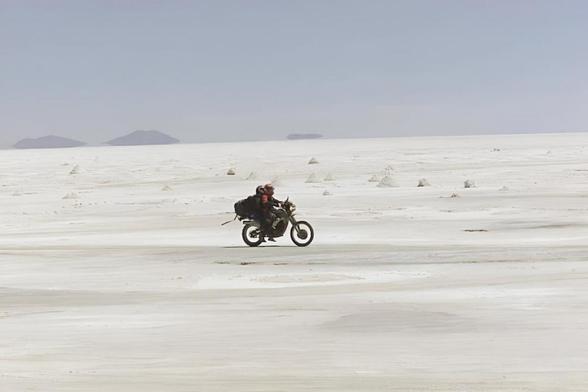 Dos personas montadas en una moto mientras atraviesan el Salar de Uyuni, el mayor desierto de sal del mundo (Getty Images)