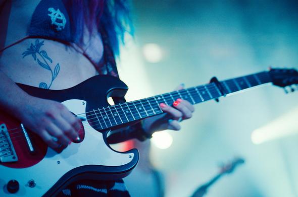 Close up on jasmine playing her electric guitar. She has colorfuled painted nails.