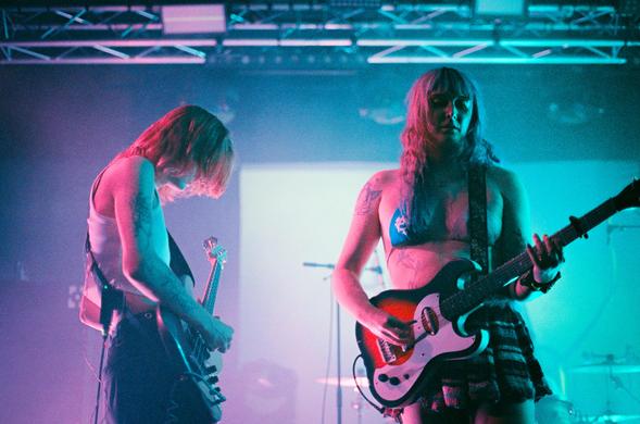 Jasmine4t with her electric guitar (right) and her bassist (left) playing side by side on stage.