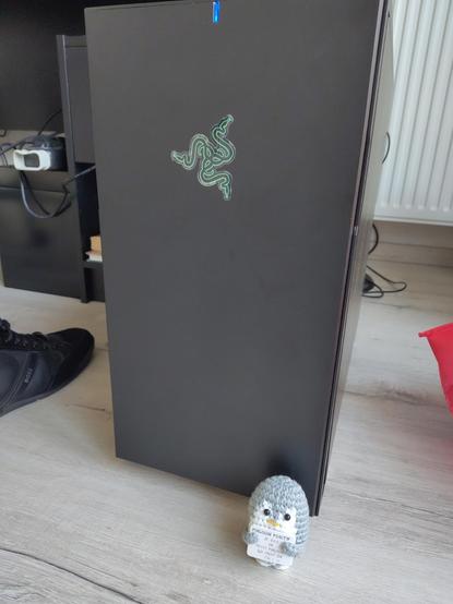 Une peluche d'un pingouin positif devant une tour de PC