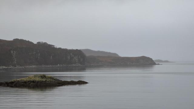 A misty, grey sea loch with some land visible though the greyness, Isle of Skye, Scotland