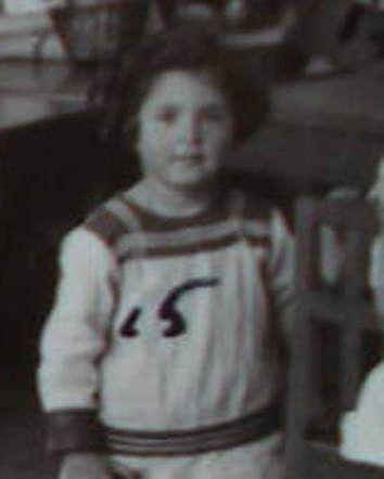 A blured photo of a young girl standing next to a chair.