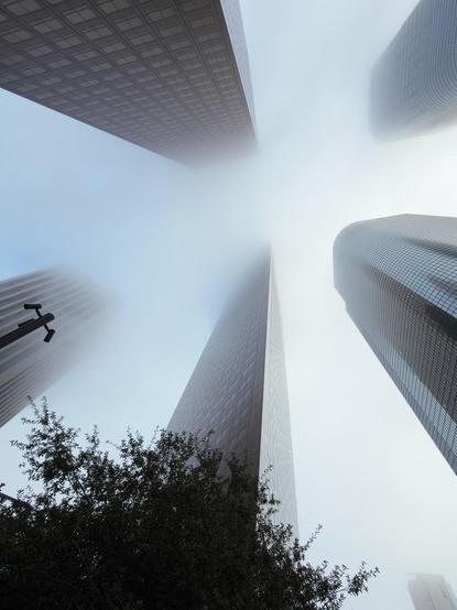 Tall buildings on Bunker Hill in Los Angeles. The view is looking straight up, and the tops of the buildings appear to vanish into the clouds.