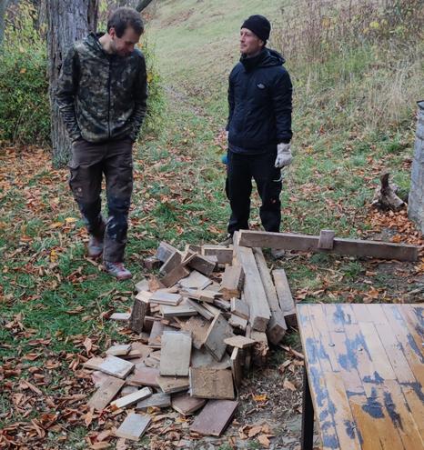 Zwei Männer stehen hinter einem Holzhaufen der aus dem alten Material gemacht wird.