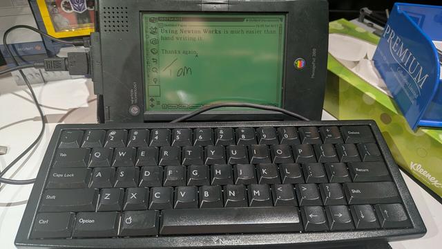 An apple newton personal data assistant, side ways with a keyboard in the foreground