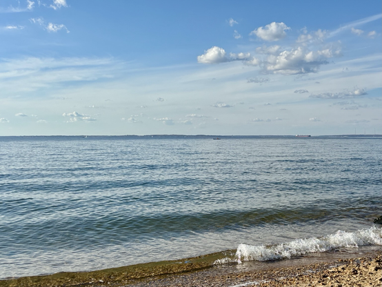 Looking NW on the Chesapeake bay. Blue skies with a few scattered clouds. Small wave crashing in the sandy shore.