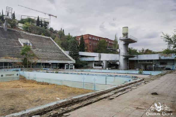 large outdoor pool with large spectator stand and diving board