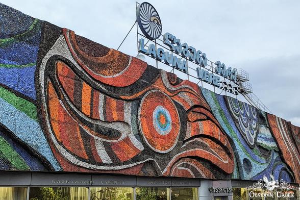 glass mural in orange blue and green, "Laguna Vere" sign above