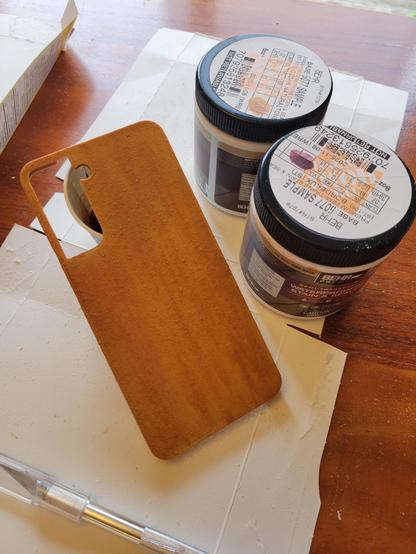 One of the phone cases stained. The two-tone stain and the lines from sanding almost gives it the appearance of wood grain. It's a warm colour, quite yellow but with nods to reds.