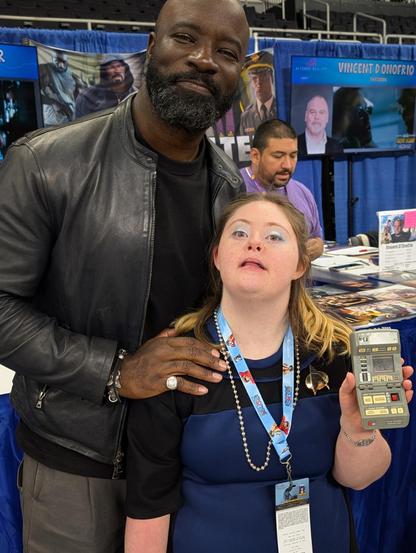 A young woman with Down syndrome cosplaying as a Starfleet officer standing next Mike Colter