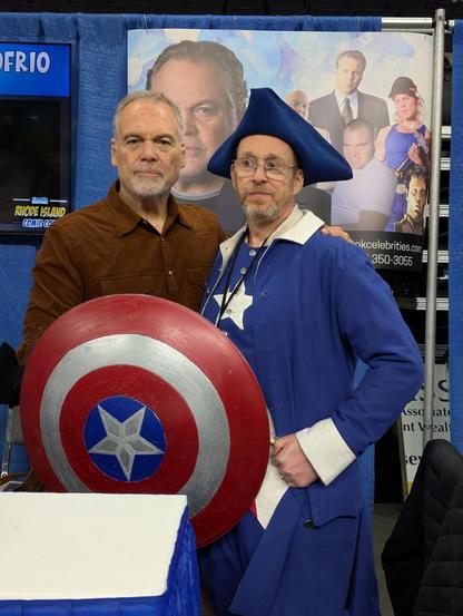 A man cosplaying as Colonial America standing next to Vincent D'Onofrio. He is holding Captain America's shield