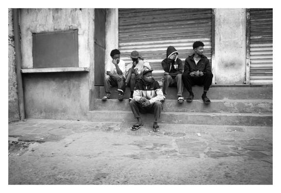 Des personnes assises sur un escalier, devant un magasin fermé.