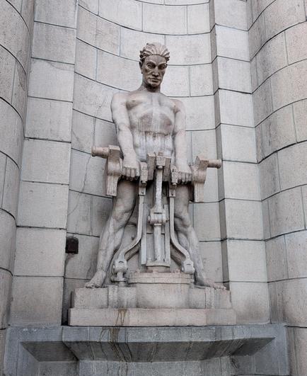 A statue of a muscle-bound naked man wielding a jackhammer