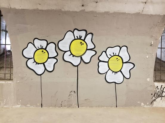 Three yellow and white flowers drawn on a concrete arch.