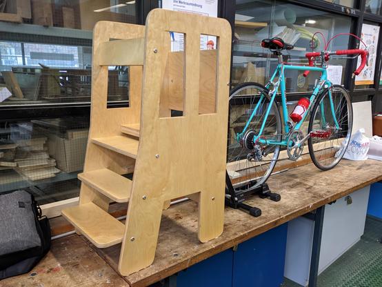 Links ein Lernturm ausHolz. Rechts ein schickes Rennrad.