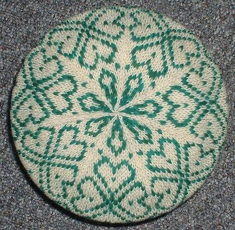 a top down photo of a green and white color work tam, the pattern looks like shamrocks.