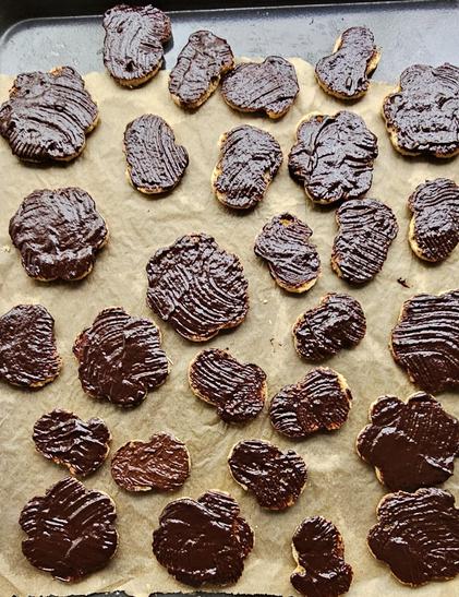 Weihnachtsplätzchen mit Schokoladenguss auf einem Backblech mit Backpapier.