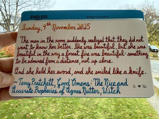 A pen quote from Terry Pratchett’s Good Omens: The Nice and Accurate Prophecies of Agnes Nutter, Witch that reads: 
“The men in the room suddenly realized that they did not want to know her better. She was beautiful, but she was beautiful in the way a forest fire was beautiful: something to be admired from a distance, not up close.

And she held her sword, and she smiled like a knife.”

Written using Noodler’s Apqche Sunset, Dominant Industry Ginger Chicken & Robert Oster Blue Water Ice.