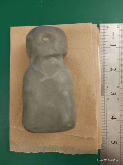 Image: Photo of a mini, grey, clay golem type figure. Approx 4 inches high on a Brown Paper Background
