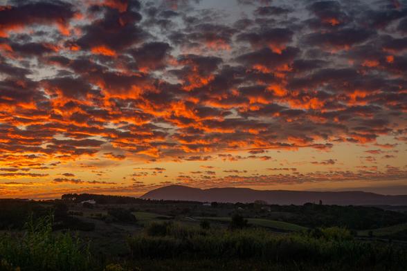 very colorful orange clouds filling the sky at sunset looking out towards Montejunto in Portugal