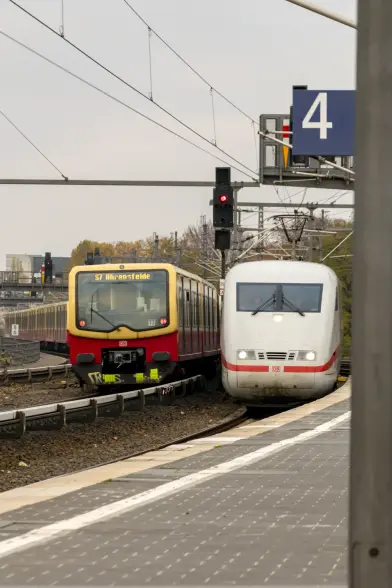 Yellow-red Berlin S-Bahn train of class 485 next to white ICE 1 train