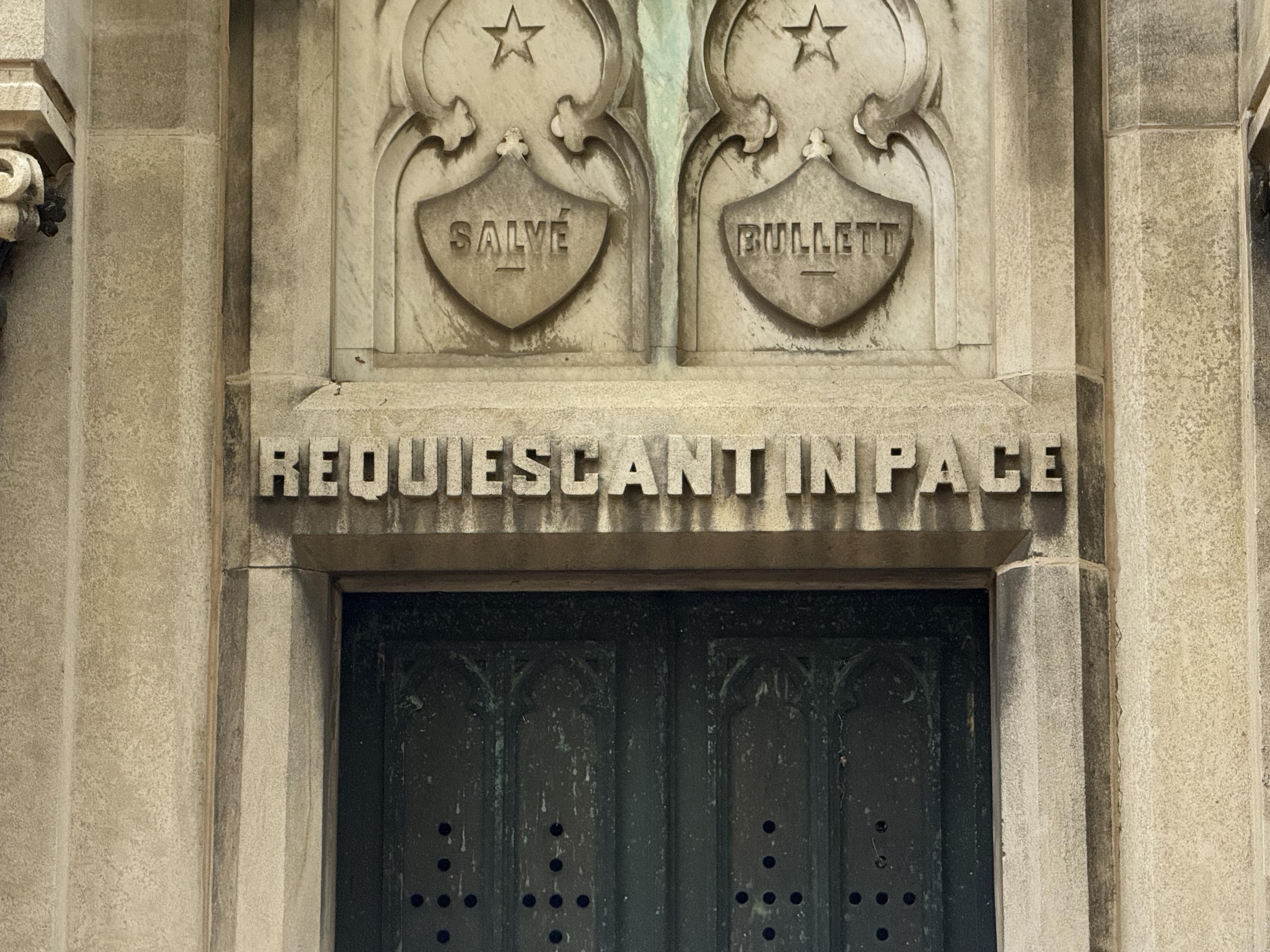 An inscription engraved above the doorway to a cemetery crypt reading REQUIESCANT IN PACE"